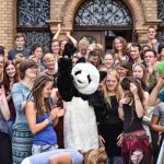 Ein Panda in der Mitte um den viele Jugendliche herum stehen
