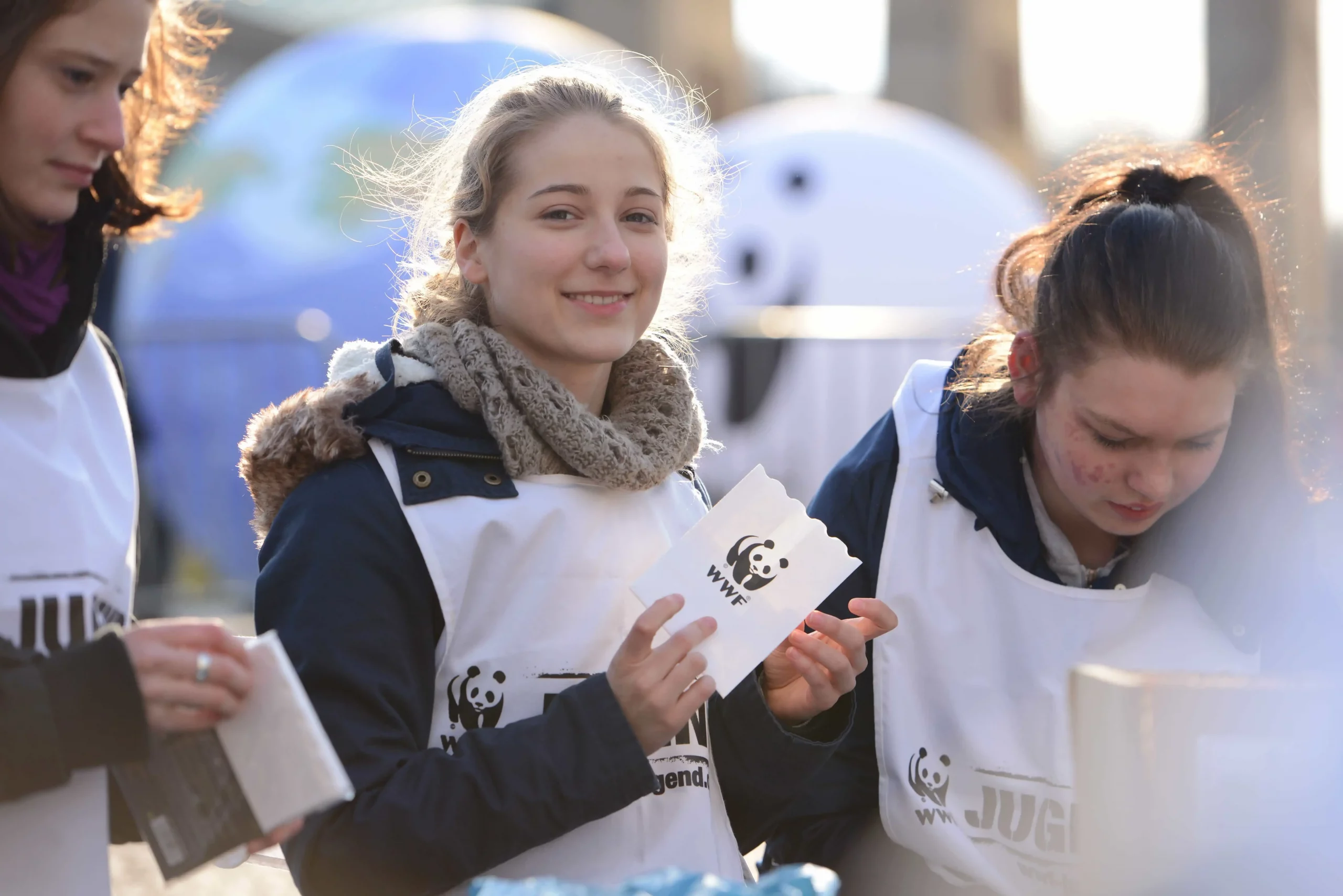 Ein Mädchen hält ein Papiertütchen mit dem WWF-Logo drauf in der Hand und schaut in die Kamera