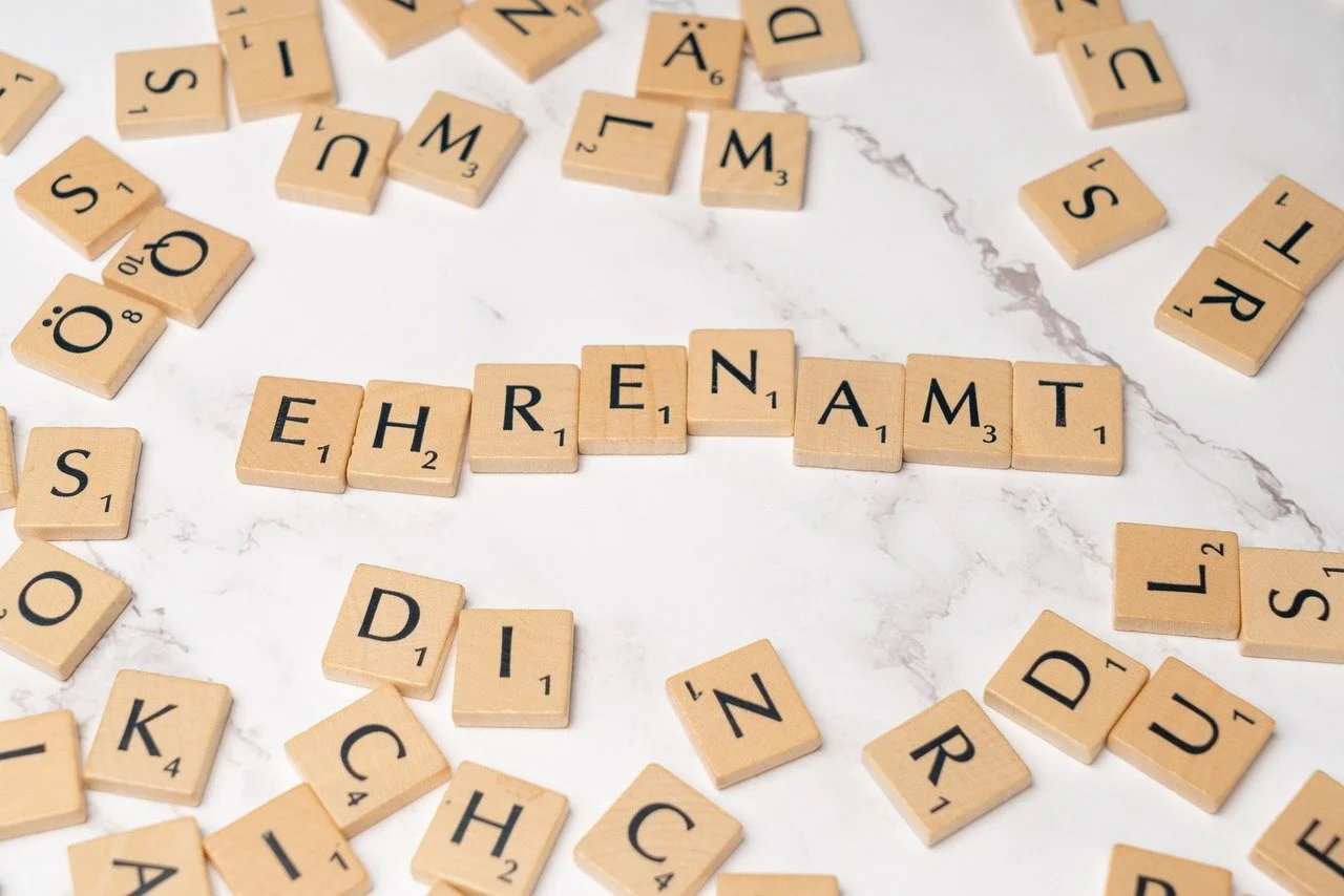 Das Foto zeigt Scrabble-Steine. Aus ihnen ist das Wort "Ehrenamt" gebildet. Weitere Steine liegen lose um das Wort herum.
