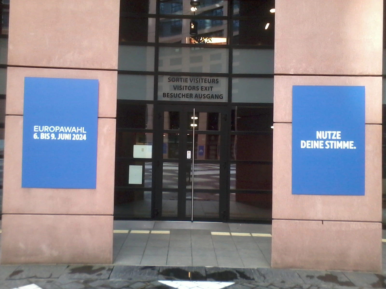 Das Foto zeigt zwei blaue Plakate: Eines mit der Aufschrift EU-Wahl 6.-9. Juni 2024, das andere mit der Aufschrift "Nutze deine Stimme". Sie hängen im Innenhof des EU-Parlaments.