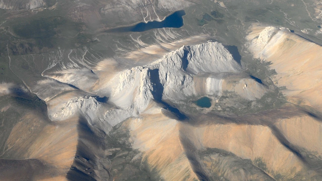 Eine karge Gebirslandschaft von oben, teilweise mit Schnee und Eis bedeckt