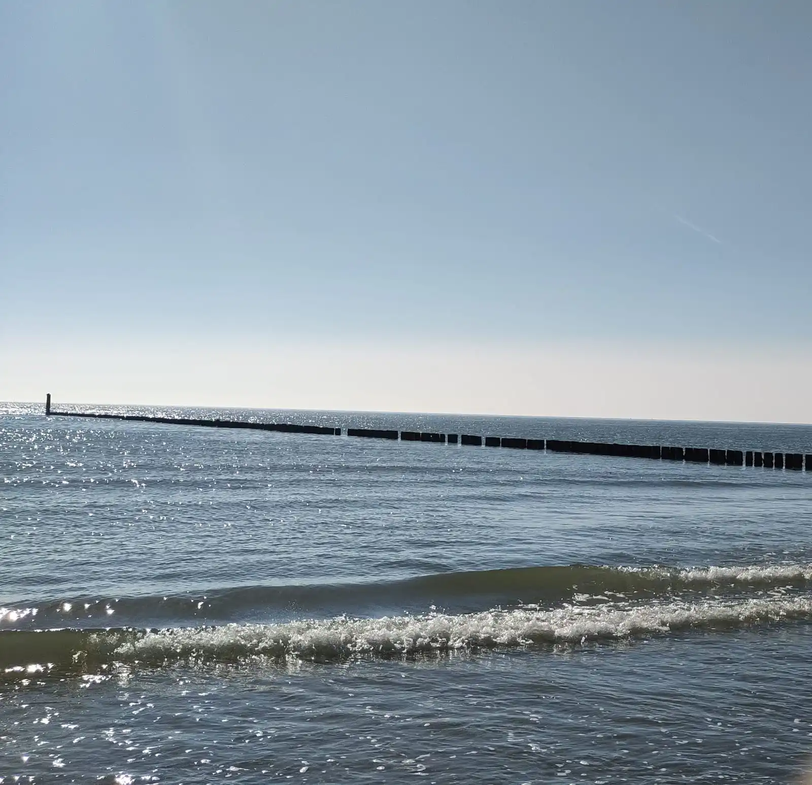 Das Bild zeigt Meerwasser und eine Landnung, die ins Meer ragt.