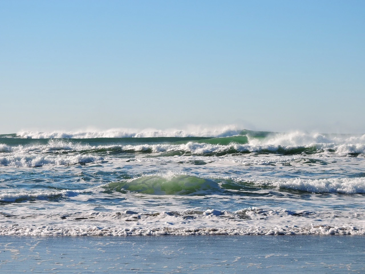 Das Foto zeigt leichte Wellen im Meer. Im Hintergrund ist blauer Himmel.