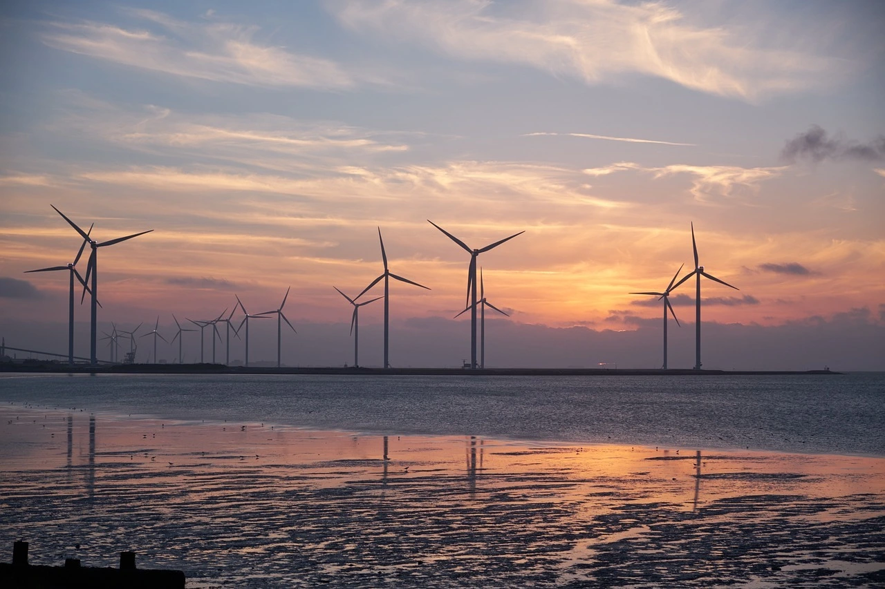 Das Foto zeigt WIndräder im Sonnenuntergang.