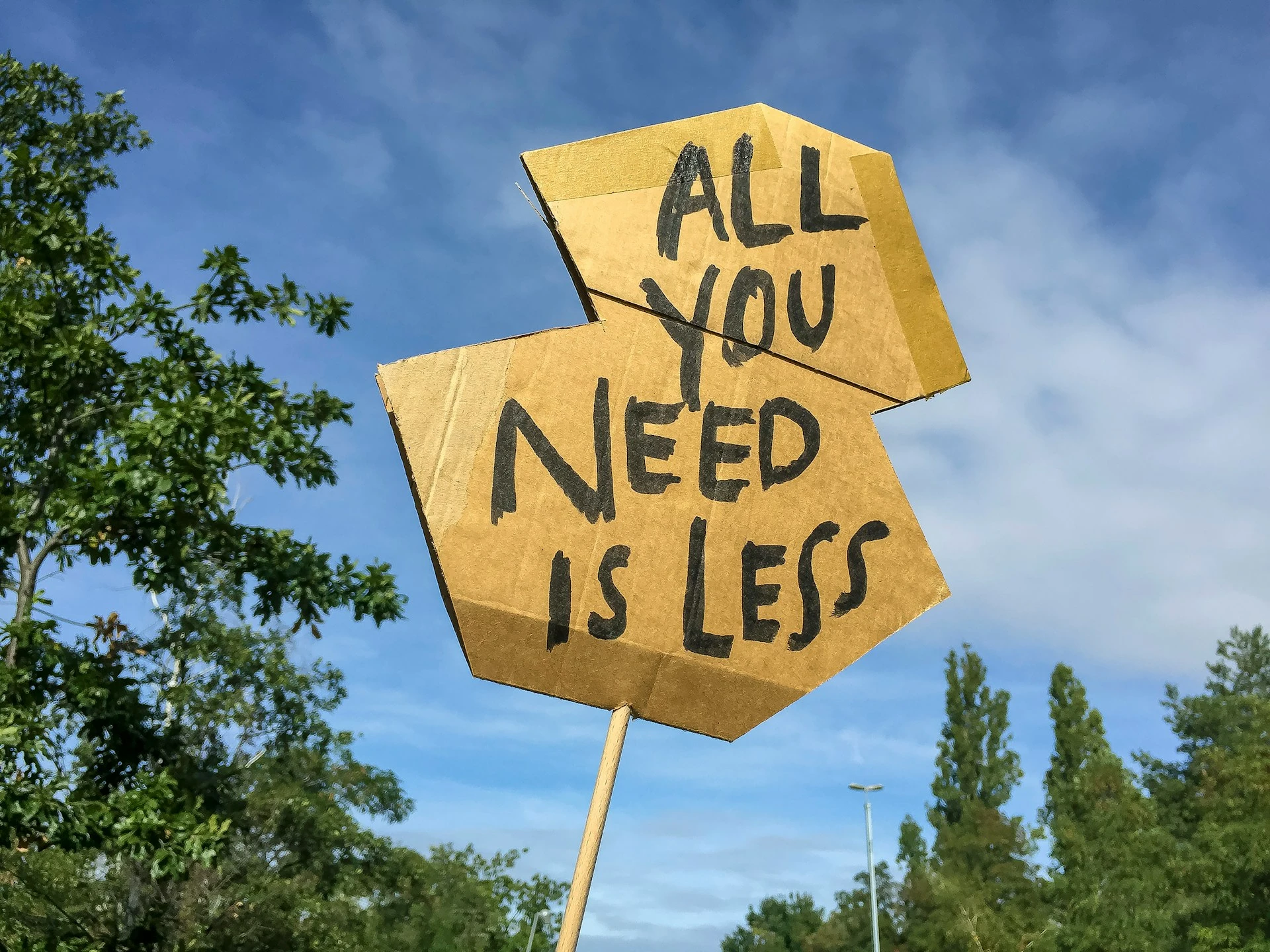 Ein Schild mit der Aufschrift "All you need is less" vor blauem Himmel