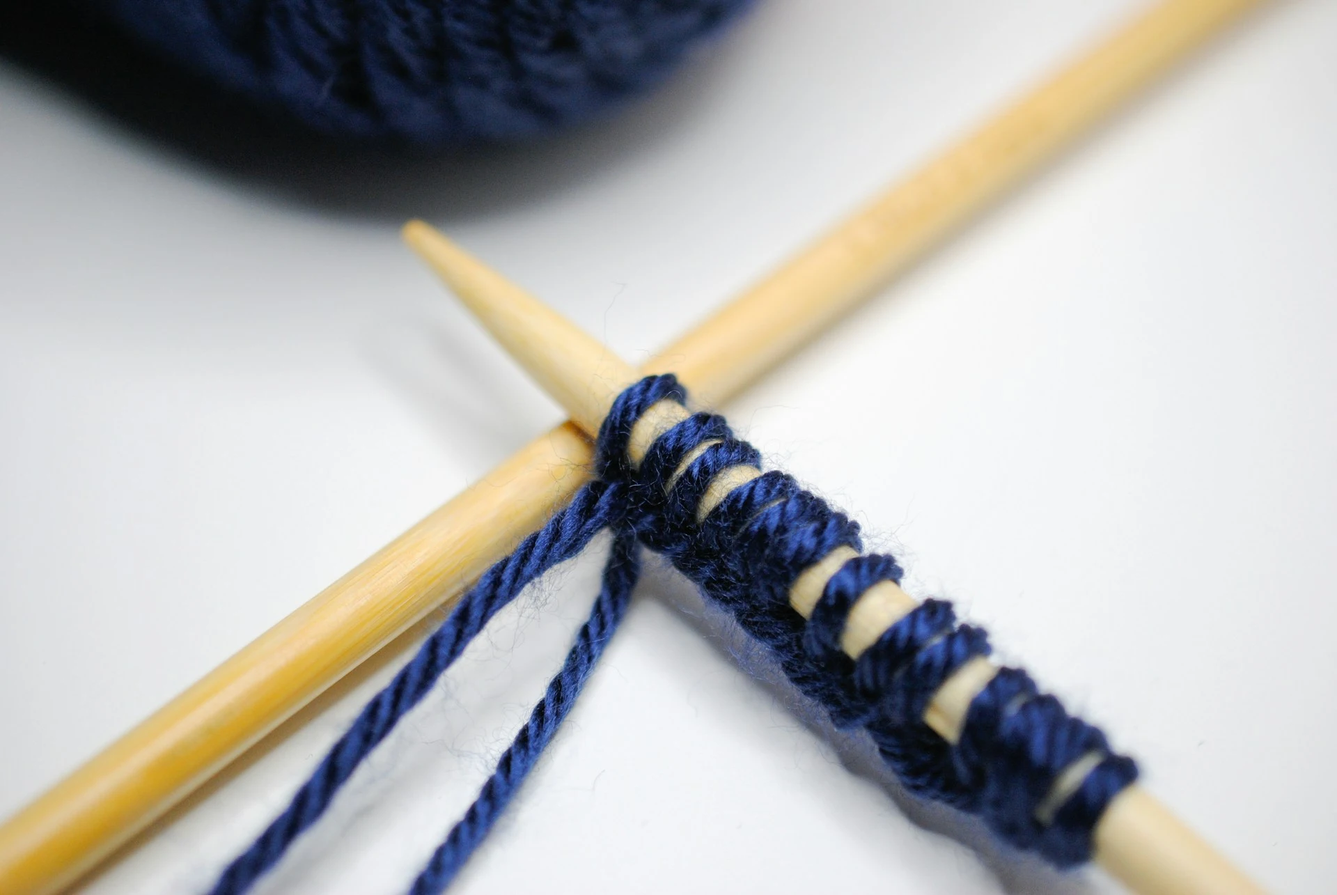 dicke Stricknalden mit dunkelblauer Wolle auf einer hellen Oberfläche