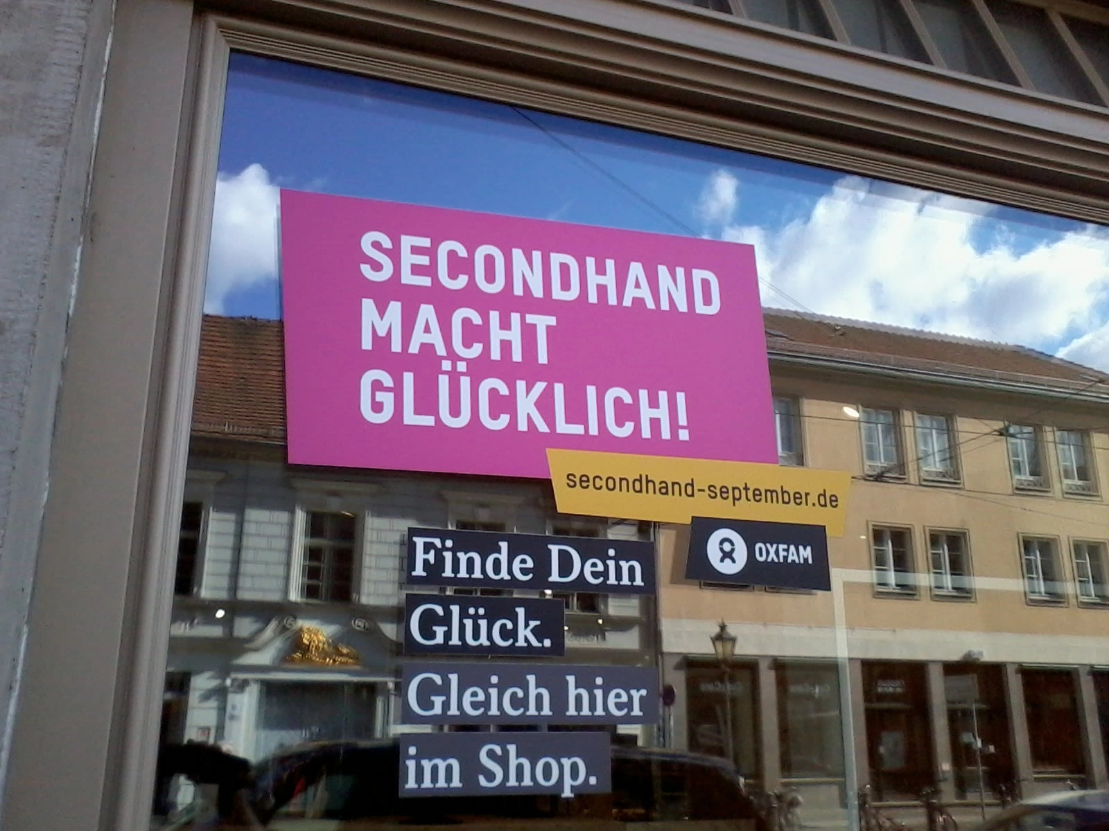 Das Foto zeigt ein Schaufenster. Darin hängt ein Plakat mit der Aufschrift "Second Hand macht glücklich"