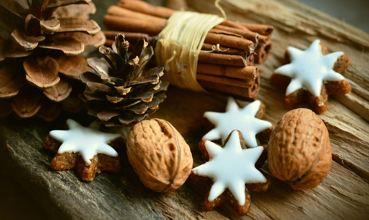 Das Foto zeigt Weihnachtsgebäck, Zimtstangen und Tannengrün auf einem Tisch.