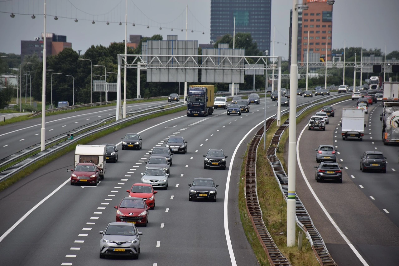 eine mehrspurige Autobahn mit Verkehr, im Hintergrund einige Hochhäuser