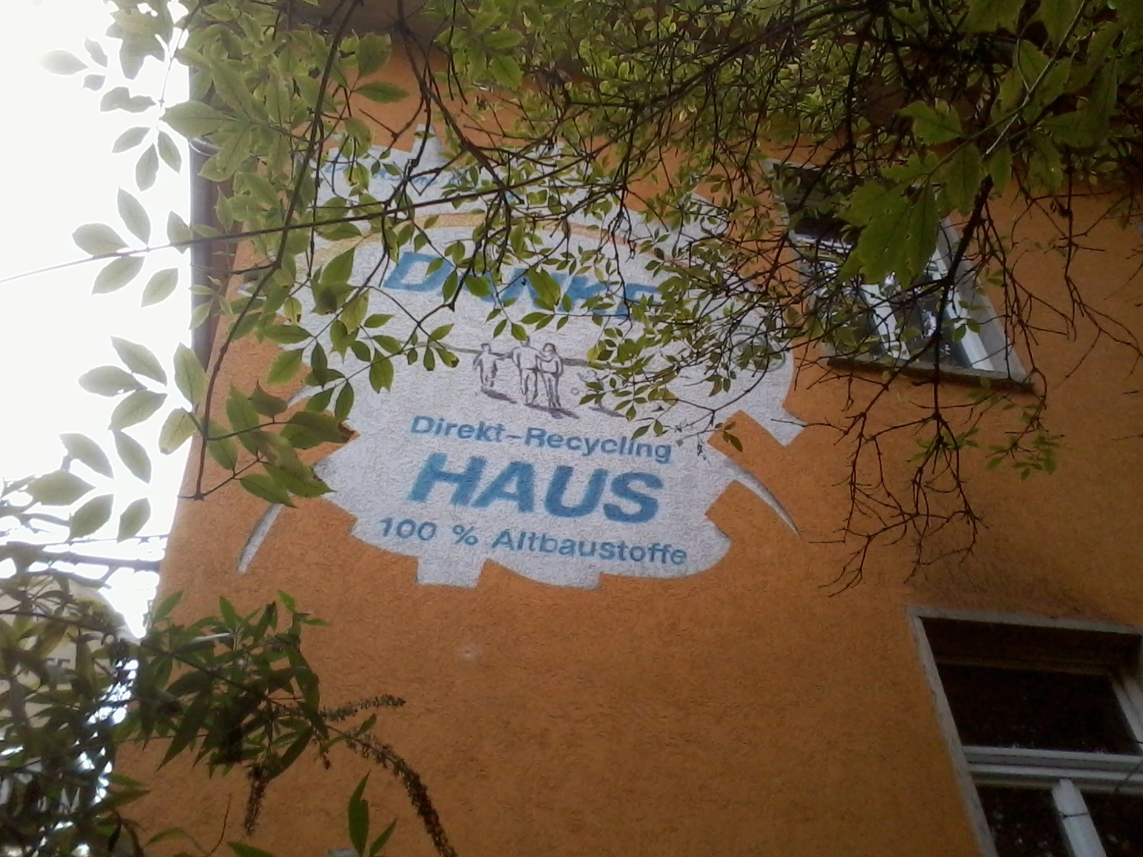 Das Foto zeigt eine Hauswand mit der Aufschrift "Direkt-Recycling Haus 100% Altbaustoffe"