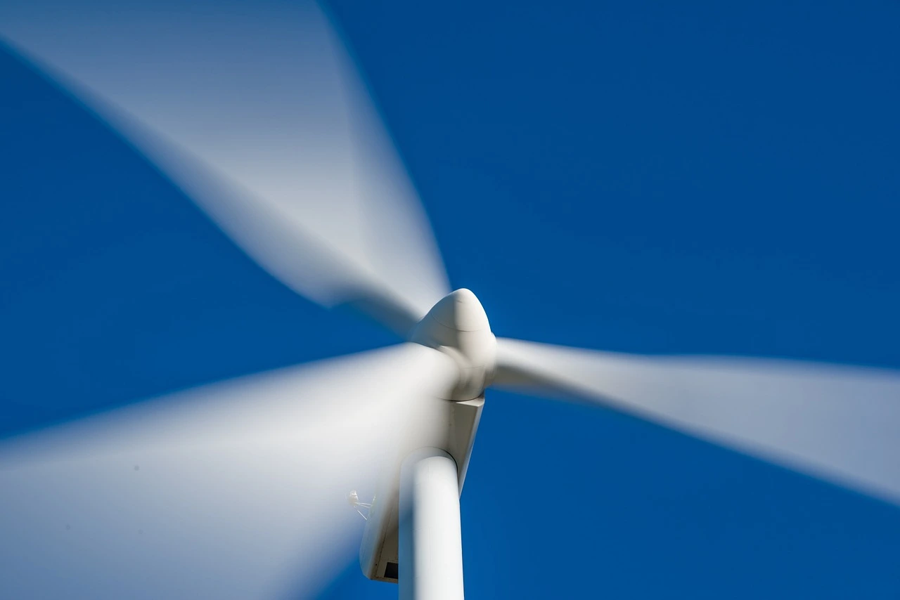 Das Foto zeigt die Rotoren einer Windkraftanlage vor blauem Himmel.