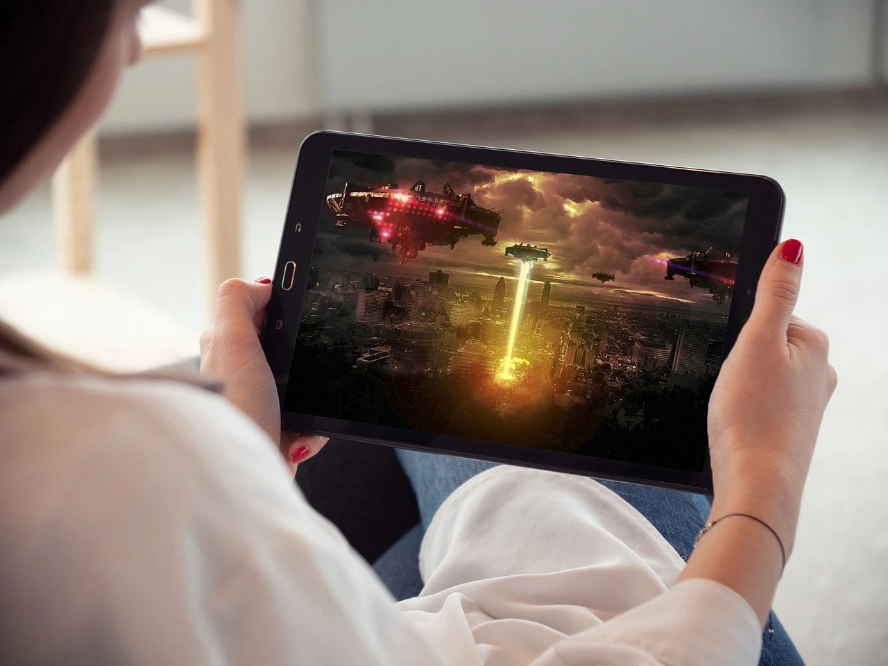 Das Foto zeigt eine Frau, die ein Tablet in den Händen hält. Darauf lauft ein Fantasy-Film.
