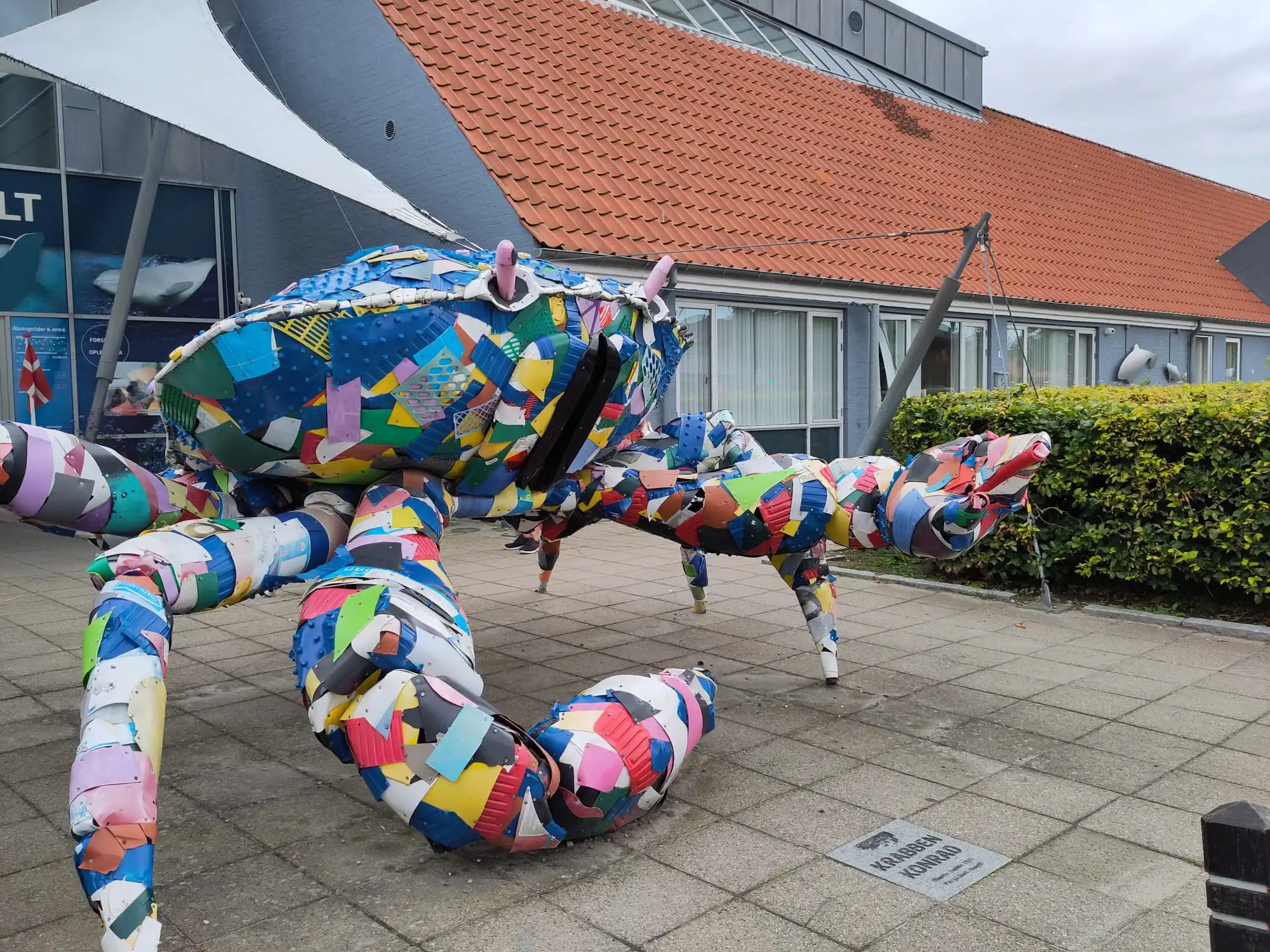 Das Bild zeigt eine Krabben-Skulptur, die aus vielen kleinen bunten Plastik Fundstücken zusammengebaut wurde.