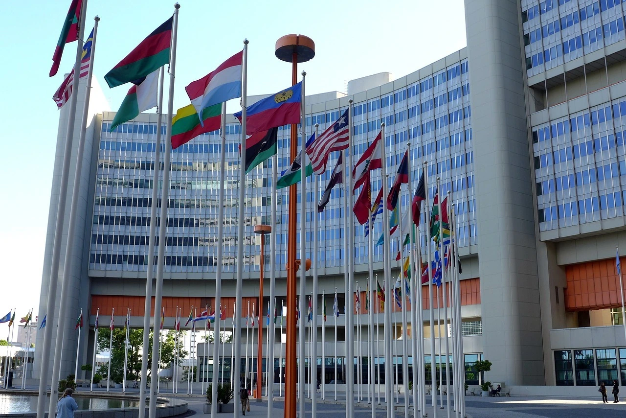 Das Foto zeigt ein Gebäude der Vereinten Nationen. Davor sind viele Flaggen zu sehen.