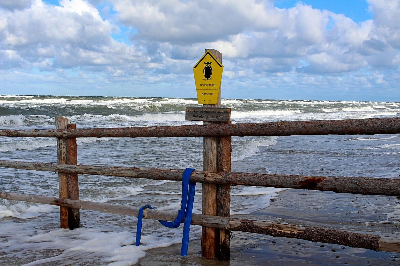 Das Foto zeigt die Nordsee. Im Vordergrund ist ein Zaun mit einem Schild "Nationalpark Kernzone". Der Himmel ist bewölkt, die Nordsee wirft Wellen.