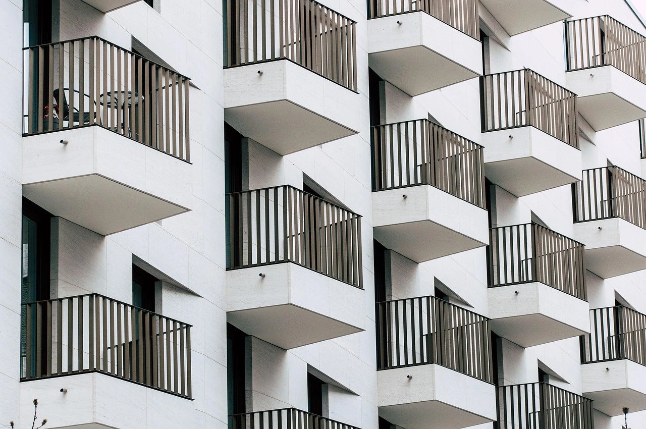 eine weiße Hausfassade eines Hochhauses mit mehreren Balkonen neben- und übereinander