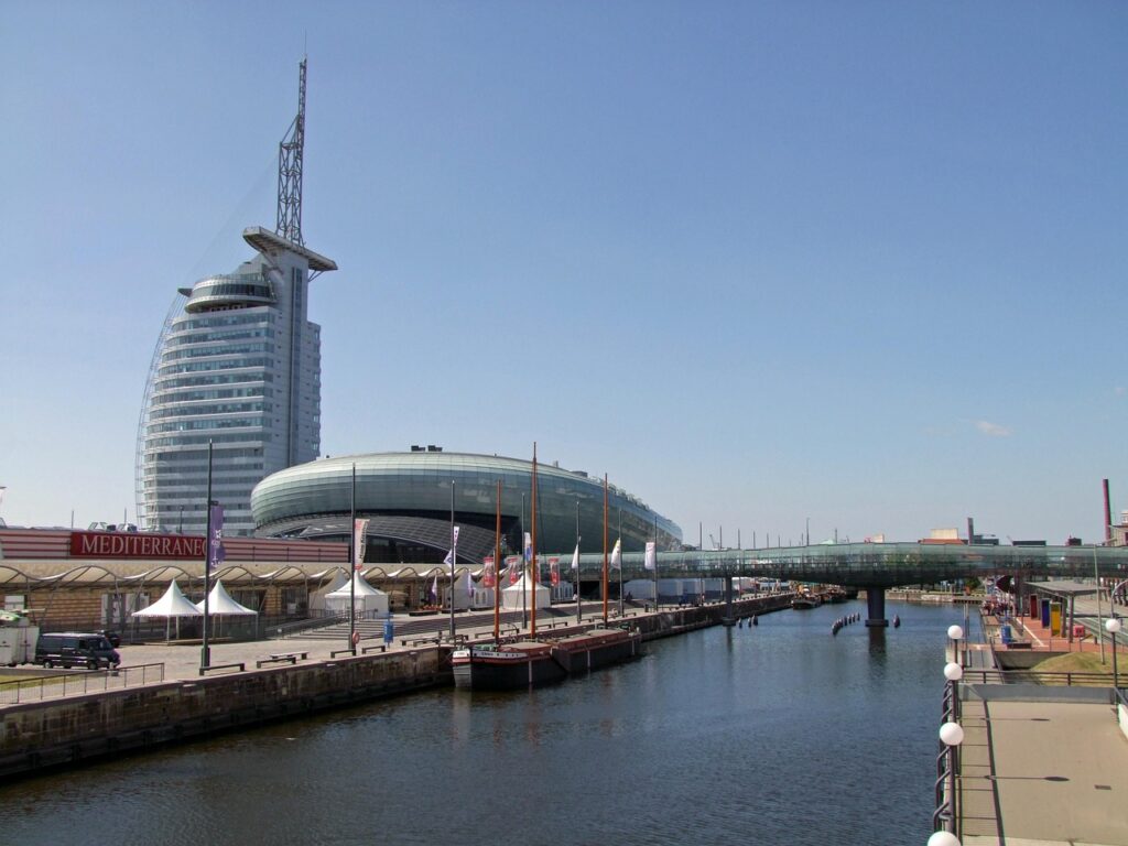 Ein walförmiges Gebäude mit einer Brücke über einen Fluss, daneben ein futuristisches Hochhaus