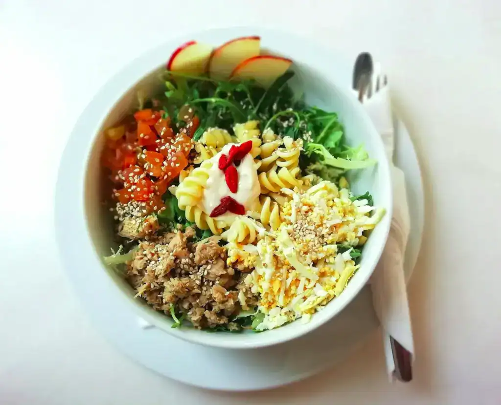 Eine Schüssel mit Nudeln, Salat und Apfelschnitzen