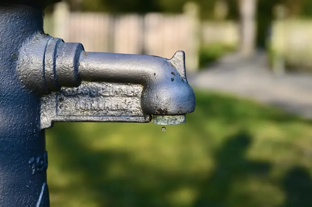 blauer Wasserhahn, aus dem ein Wassertropfen kommt