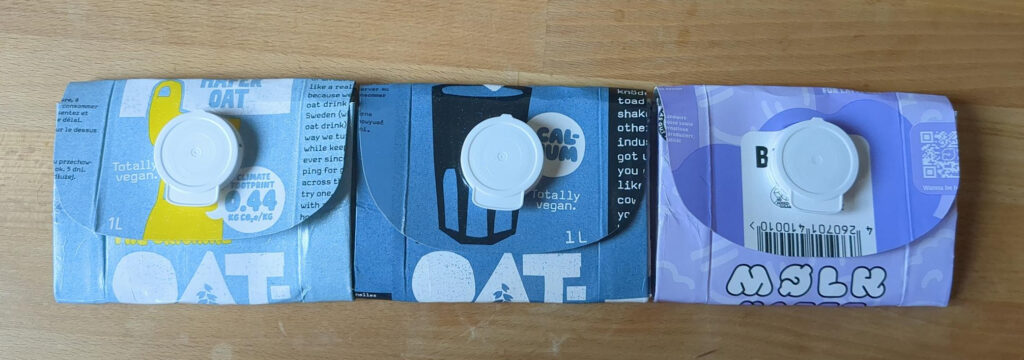 Drei unterschiedliche Milchtüten-Portemonnaies mit Klappverschlüssen nebeneinander. Von links nach rechts: hellblau, dunkelblau und hellviolett.