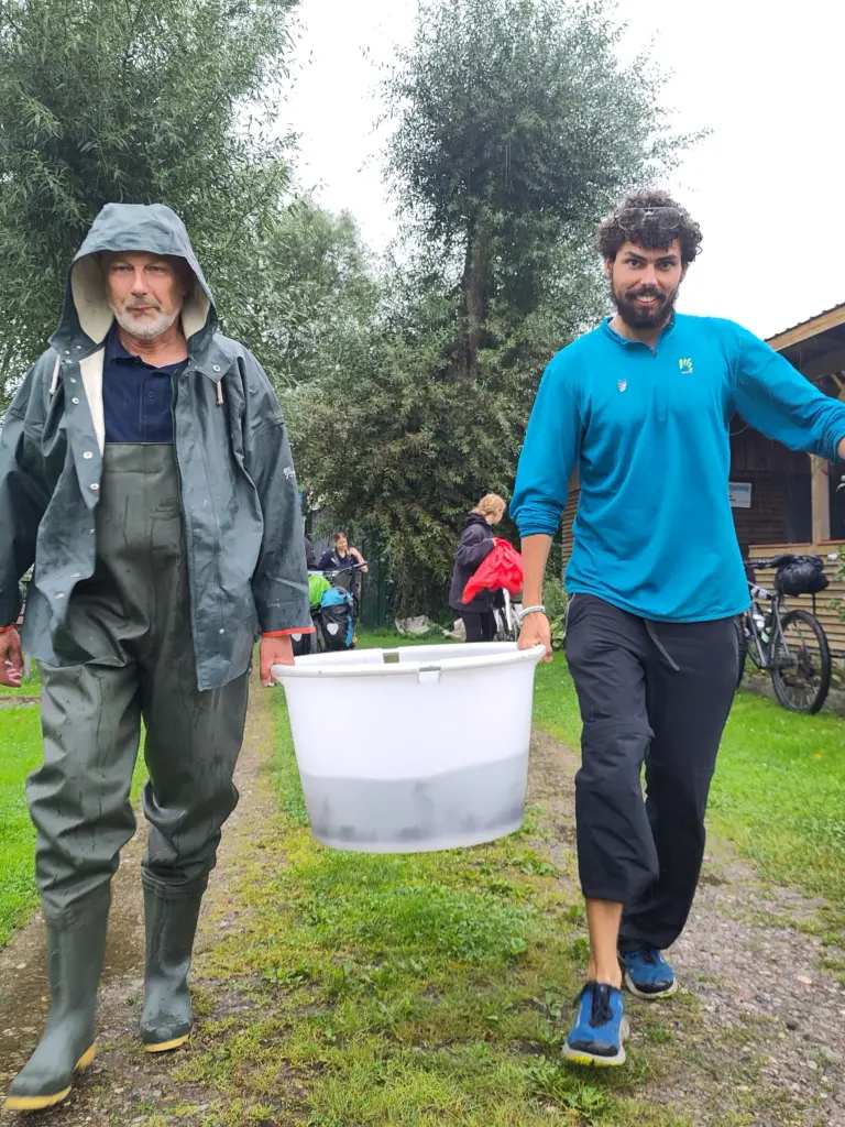 Der Leiter der Aufzuchtstation Jörn Gessner und WWF Jugend Justin tragen einen Eimer voller Störe zum Fluss.
