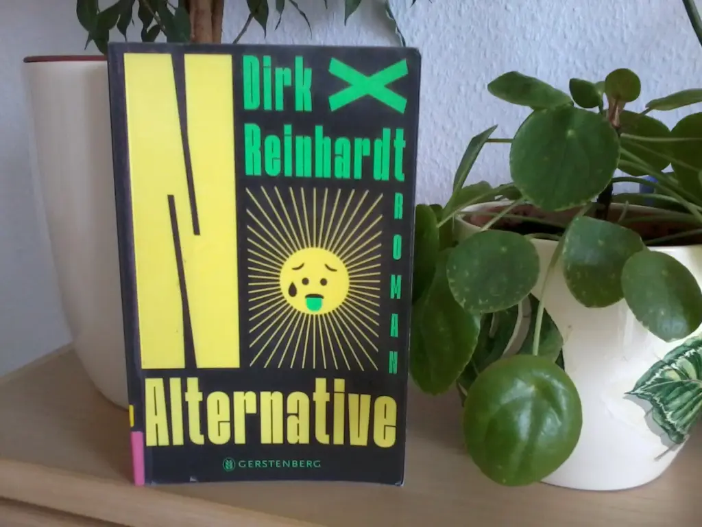 Das Buch "No Alternative" steht vor zwei Grünpflanzen