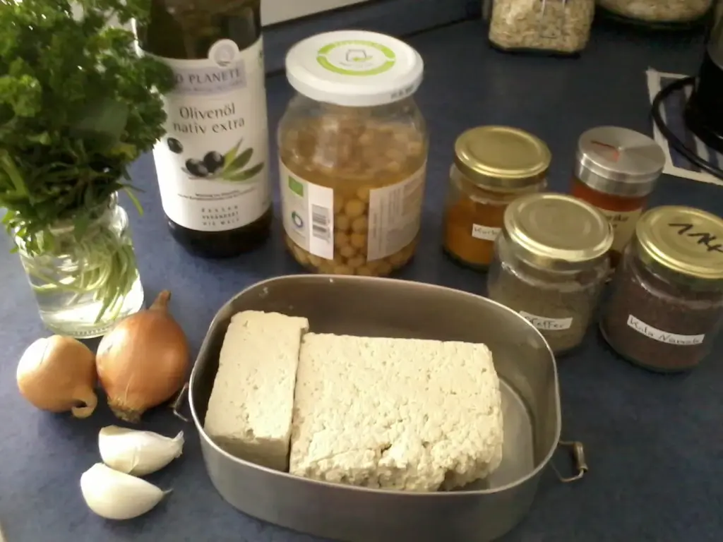 Das Foto zeigt die Zutaten für das vegane Rührei auf einer dunkelblauen Arbeitsfläche.