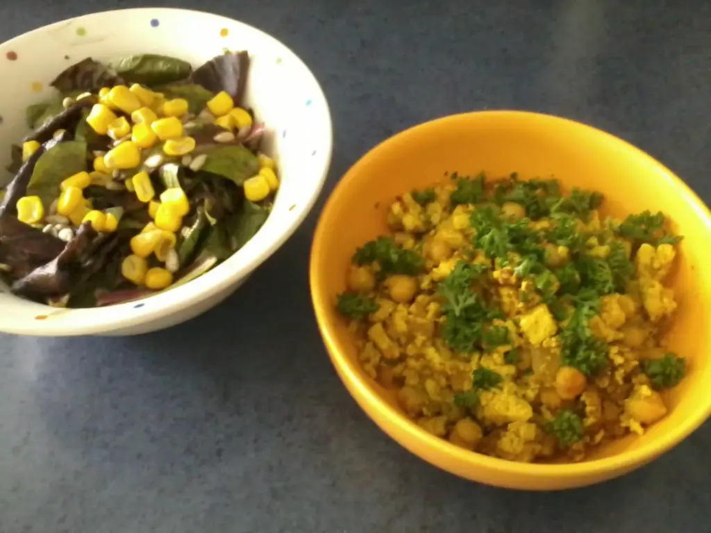 in einer gelben Schüssel das Tofu-Rührei, bestreut mit Petersilie, links daneben eine Schüssel mit Salat