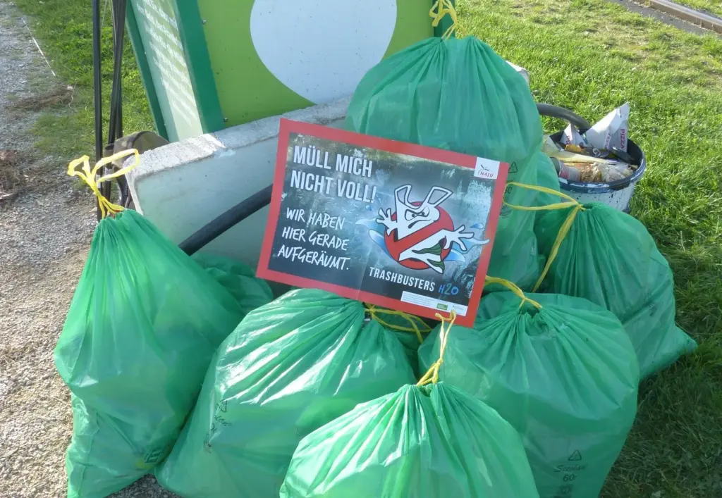 Das Bild zeigt einen Stapel gefüllter Müllsäcke und ein Plakat mit der Aufschrift Müll mich nicht voll! Wir haben hier gerade aufgeräumt.