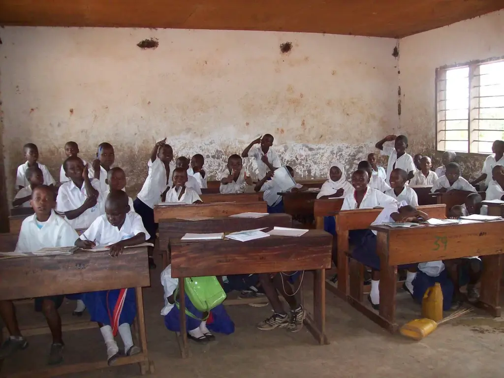 ein Klassenzimmer in Afrika, die Schüler:innen tragen weiße Hemden und blaue Röcke/Hosen