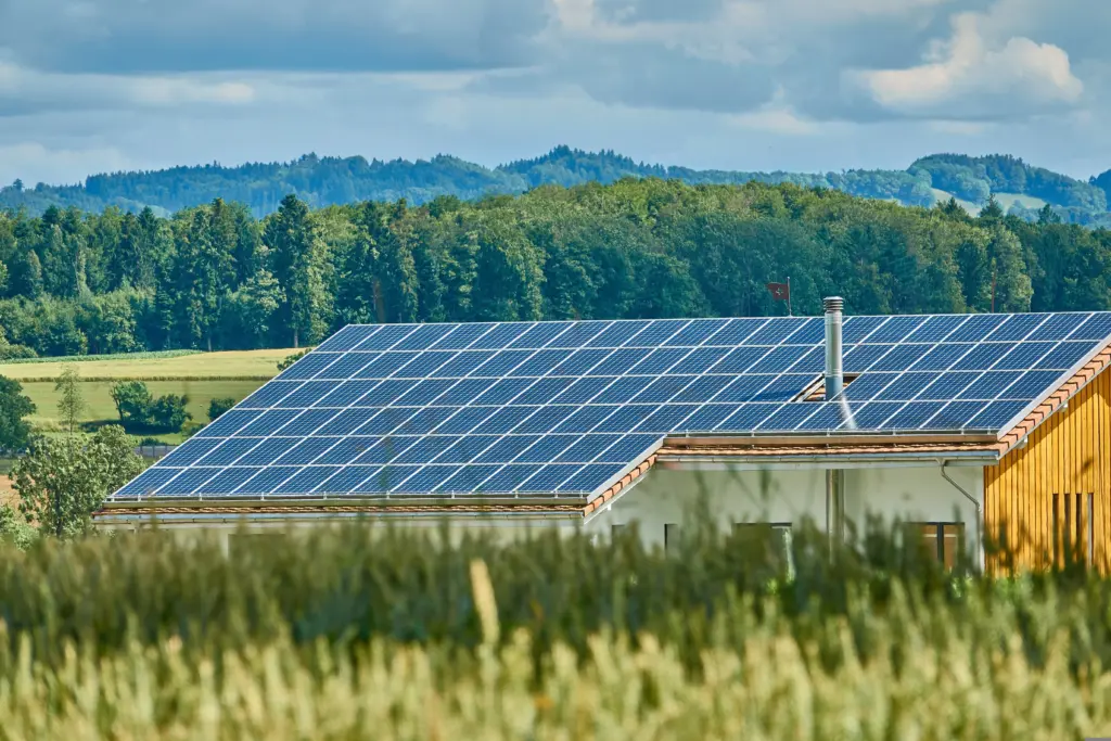 Haus vor grünen Wäldern mit Photovoltaikanlage auf dem Dach. Photovoltaikanlagen auf Wohnhäusern könnten sich in Zukunft weniger rentieren.