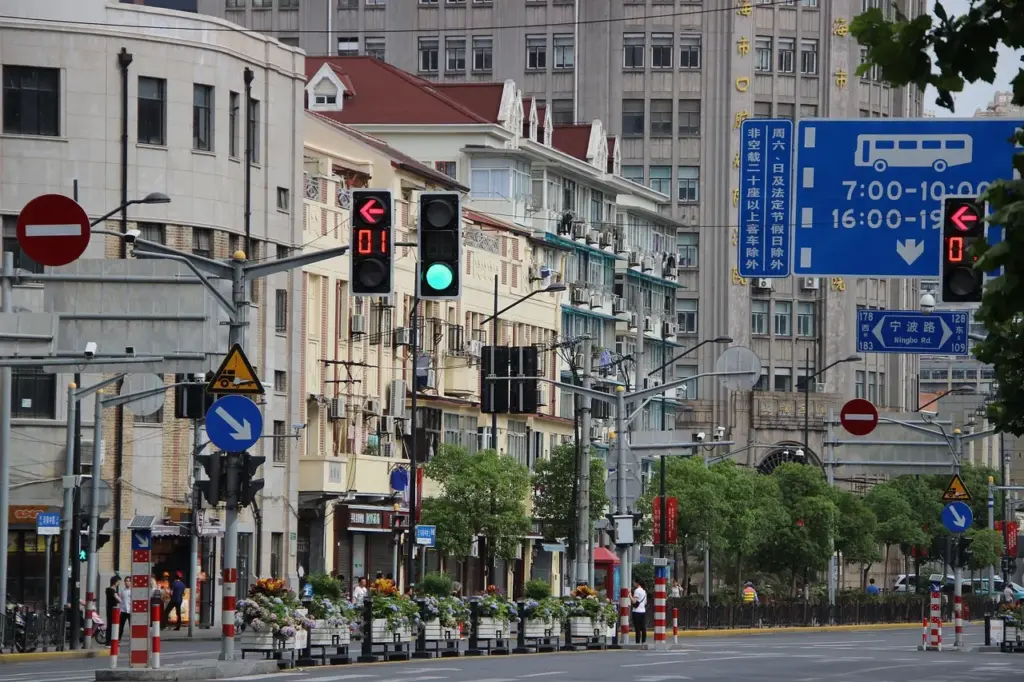 eine Straße in China, links eine hohe Häuserreihe, rechts und in Vordergrund dominieren Verkehrsschilder