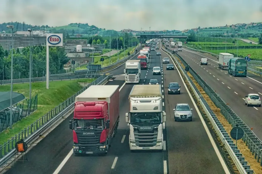 viele LKW und Autos fahren auf einer mehrspurigen Autobahn, am linken Fahrbahnrand ein ESSO-Schild