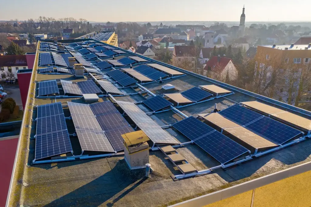Blick auf ein Hausdach mit mehreren Solarmodulen, im Hintergrund weitere Häuser